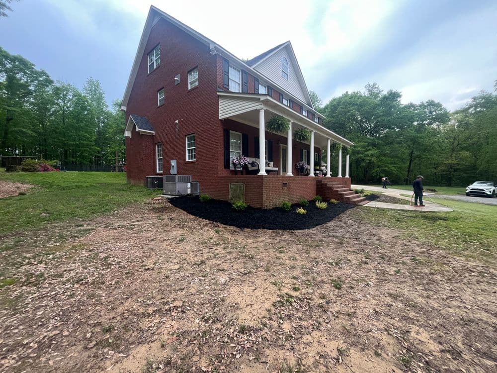 Beautiful red brick house with landscaped front yard and porch, surrounded by trees.