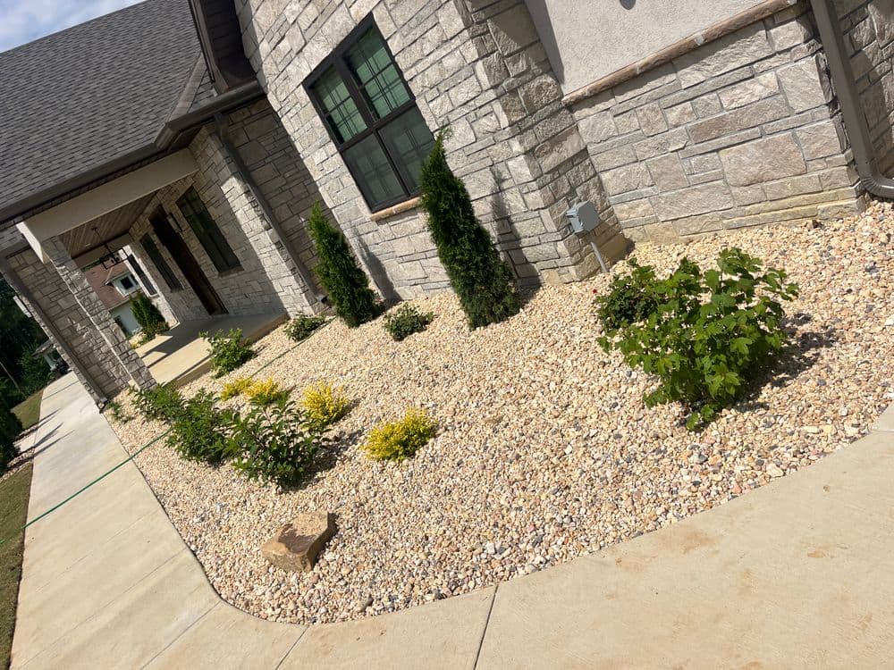 Modern house exterior with stone facade, decorative landscaping, and gravel garden beds.