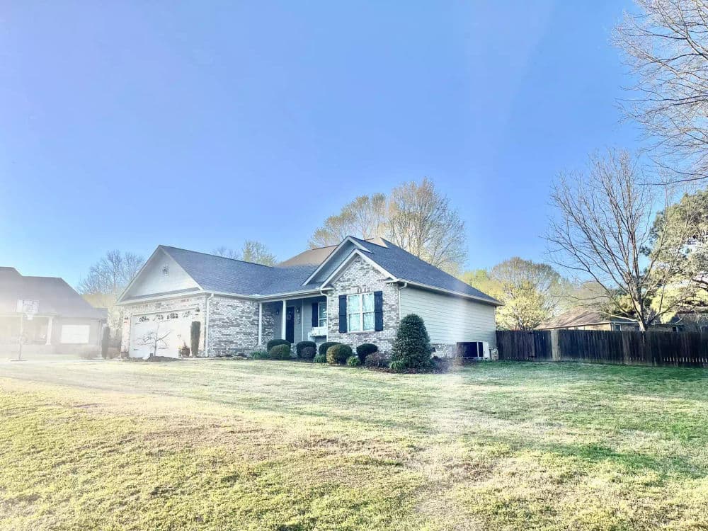 Charming single-story house with stone exterior and manicured lawn in sunny neighborhood.