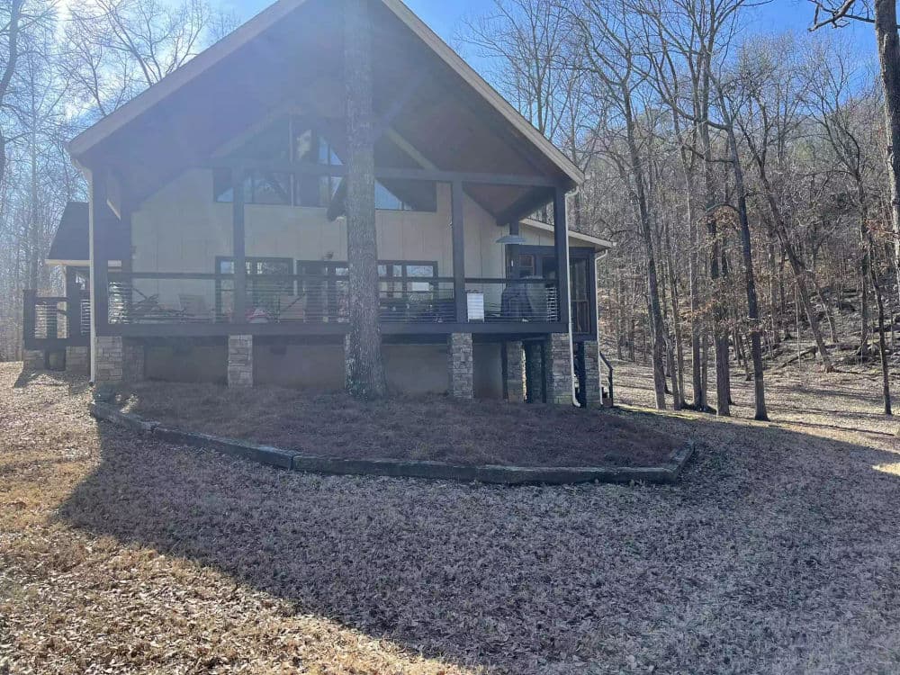 Modern cabin surrounded by trees, featuring a spacious deck and natural landscaping.